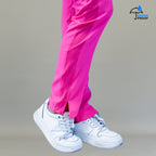 Detalle del dobladillo con abertura lateral en el pantalón quirúrgico rosa fiusha sobre tenis blancos.