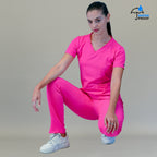 Modelo en cuclillas vistiendo el conjunto completo con pantalón quirúrgico 530 rosa fiusha de frente.