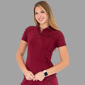 Three-quarter view of the burgundy 920 scrub top with the model smiling and hands clasped.