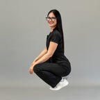 Side crouching view of women’s Style 945 Black scrub jumpsuit