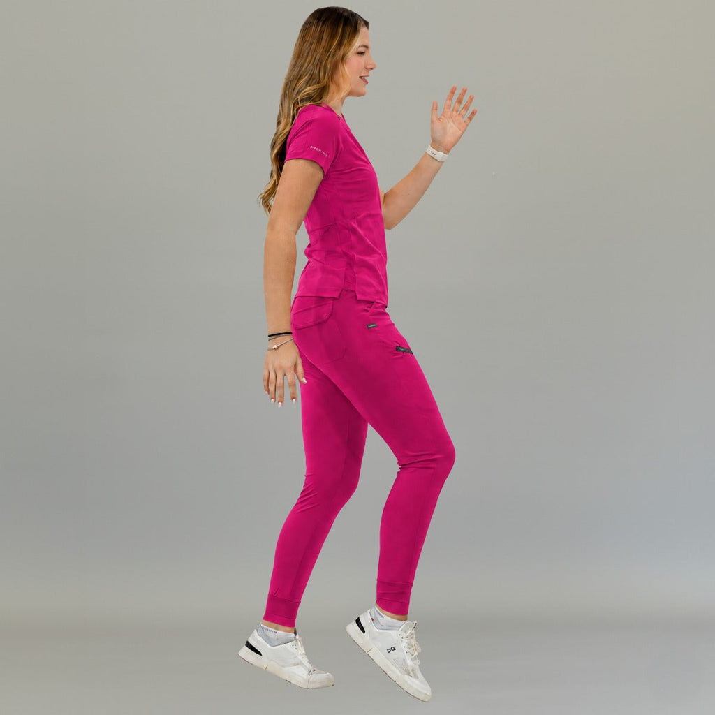 Side view of women's Style 905 fuchsia short-sleeve scrub top on a walking model