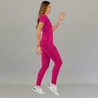 Side view of women's Style 905 fuchsia short-sleeve scrub top on a walking model