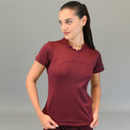 Woman wearing maroon Women's Top 910 Super Stretch Scrubs, looking to the side with hands near hips.