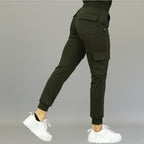 Back-side angle showing olive green women's jogger pants 910 with one leg extended backward.