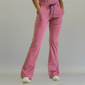 Women's mauve rose flare scrub pants, front view with one leg crossed