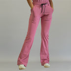 Women's mauve rose flare scrub pants, front view with one leg crossed