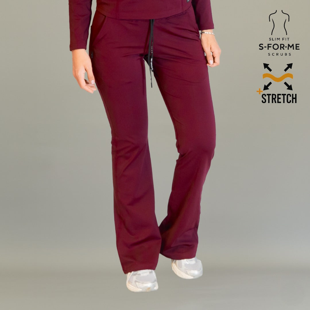 Women’s 915 Super Stretch maroon flare scrub pants front view with drawstring waist and white shoes